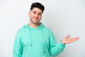 Young caucasian man isolated on white background holding copyspace imaginary on the palm to insert an ad