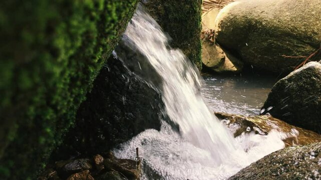 A dense stream of a mountain stream pours onto the rocks in the jungle