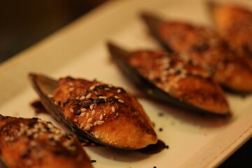 A white plate with musselings covered in sesame seeds, great for food presentation and photography.