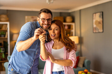 A couple is standing together, happily showing the key to their new home. The image captures excitement, achievement, and a fresh start as they celebrate homeownership in a joyful moment.