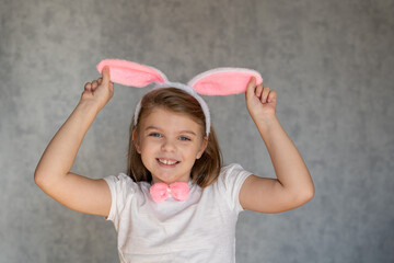 Cheerful girl with bunny ears on gray background. Easter Holiday.