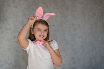 Cheerful girl with bunny ears on gray background. Easter Holiday.