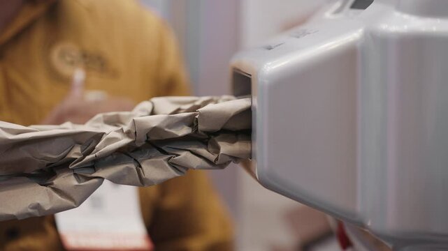 Male operator oversees a machine producing paper cushioning for packaging. Sustainable logistics and shipping concept. Eco-friendly alternative to plastic fillers.