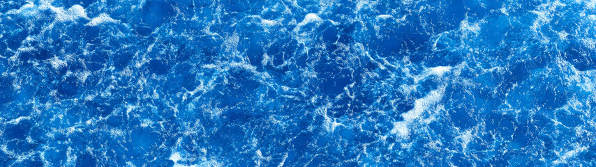 Obraz premium Stunning image of powerful and dynamic blue ocean waves crashing into the coastal shoreline creating a dramatic display of foamy splashes and turbulent water movement