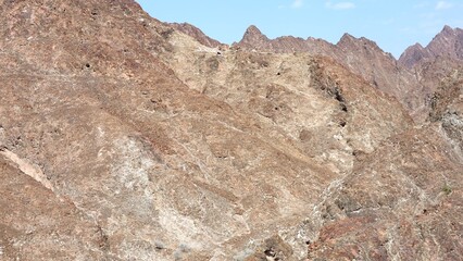 Mountains reveal rocky history, ridges shaped by erosion, erosion creating intricate patterns, layers showcasing erosion impact, rocky surfaces telling geological story, mountains framing formations.