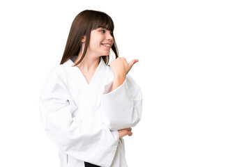 Little Caucasian girl doing karate over isolated background pointing to the side to present a product