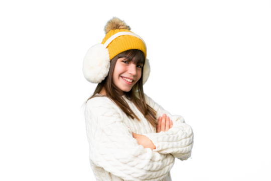 Little caucasian girl wearing winter muffs over isolated background with arms crossed and looking forward
