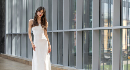 Fashion portrait of a young beautiful brunette girl in white dress