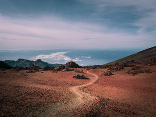 A hiking path through the arid volcanic desert with red sand and rocks on GR131 from Pico del Teide...