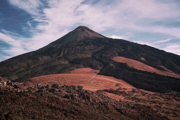 Dark lonely mountain of Pico del Teide with black lava in the volcanic arid desert during hot summer day when hiking GR131, Tenerife, Canary island, Spain