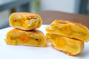 Delicious Cantonese moon cake with lotus seed pastry and salted egg yolk for Mid-Autumn Festival food mooncake on gray table background, holiday celebration serving.