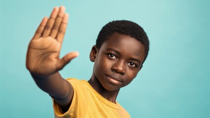a young boy with a determined expression, raising his hand in a stop gesture. The image captures a sense of resilience and strength, conveying a message of defiance and empowerment