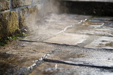 Fototapeta premium Close up view of dirt and grime being removed from stone pavement with steam rising from water. Generative AI