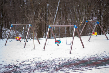 Snow-covered playground equipment in winter, with no children playing