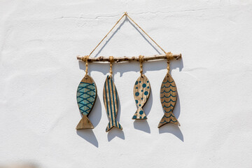 Petits poisson en bois de décoration sur le mur d'une maison en bord de mer.