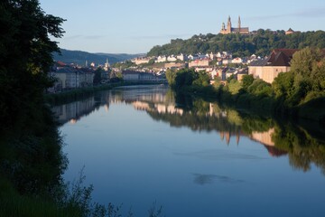 Obraz premium Serene Riverside Landscape with Town and Historic Church on Hill