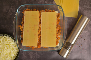 Top view. Homemade lasagna cooking preparation. Lasagne pasta sheets, Bolognese and béchamel...