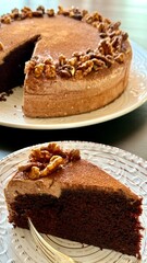 Chocolate cake decorated with walnut on white plate, black background
