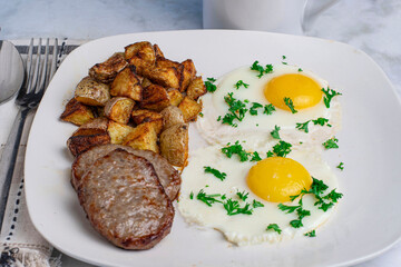 two  fried eggstop with parsleyserved with  sausage pattioes