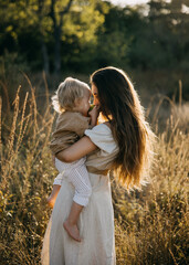A mother holds her child close in a sunlit field as they share a tender moment