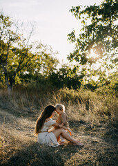 A mother and child share a tender moment in a sunlit field, their foreheads touching.