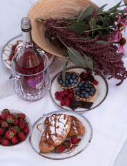 Beautiful picnic with rose wine, strawberries and berries. A cake with fruit on top of a table