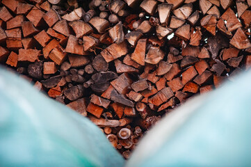 Wood log stack with out of focus blue wrapped hay bales in the foreground