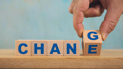 A hand is reaching for a wooden block with the letter G on it to change the word CHANGE to CHANCE.