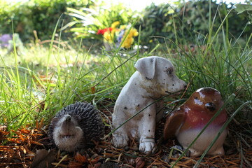 Three small animal statues nestled in the grass.