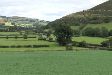 A lush green valley stretches between rolling hills. 