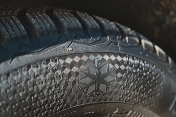 Close-up of snowflake symbol on winter tire tread.
