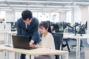 オフィスのデスクで打ち合わせをする男女のビジネスパーソン