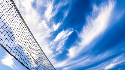 Yellow colored summer games ball against blue sky, beach volleyball or tennis net background for sport events, with ample copy space for branding, promotion, or event advertisements
