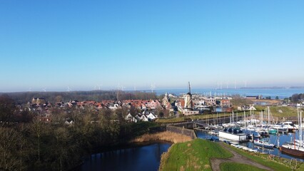 Fototapeta premium A park image in the Netherlands. An autumn season with bare trees and a walking path. A well-trodden path that leads to the water of a lake and a view of Willemstad with the mill of the village.