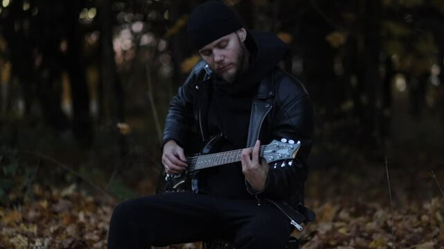 man plays electric guitar gloomily outdoors in cloudy weather