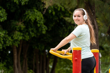 Mujer contenta entrenando sus piernas con una máquina pública del parque de su ciudad