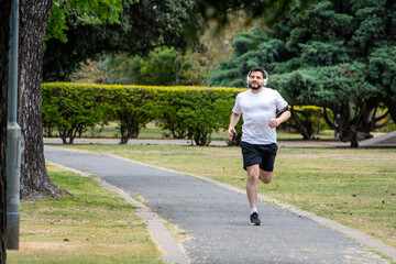 Hombre entrenando y sonriendo en un parque urbano en un hermoso día soleado. Hombre feliz corriendo