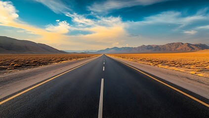 Naklejka premium A long straight road stretches across a vast arid landscape under a dramatic sky with mountains in the distance conveying a sense of journey adventure and the open road