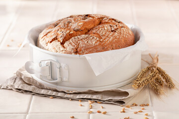 Healthy round loaf bread baking with ears and grain.