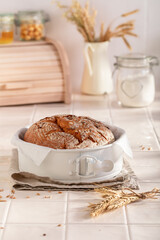 Healthy round loaf bread in white baking baking tray.