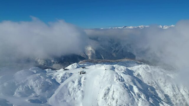 Aerial view of Vogel Ski Resort in Slovenia during winter with blanket of snow covers the slopes and ski lifts in the alpine landscape.  Features the striking peaks of Orlove and Pick Sija