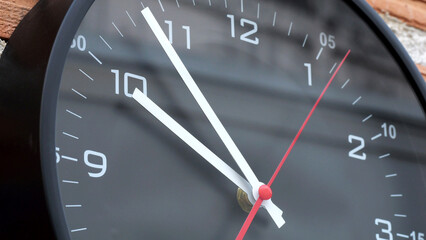 Black Wall Clock Close-Up with Red Second Hand.