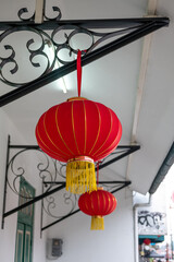 Two vibrant red Chinese lanterns illuminate a white building, adding a touch of festive tradition to the urban landscape. These symbols of good luck and happiness enhance the architectural detail with