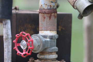 Rusty Valve on Pipe: Close-up of an old, rusty valve on a metal pipe, showing signs of wear and age. The red valve wheel contrasts against the weathered metal.