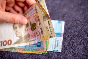 Hand holding Ukrainian hryvnia banknotes of various denominations