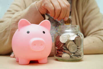 Retired elderly woman counting coins money with piggy bank and worry about monthly expenses and...
