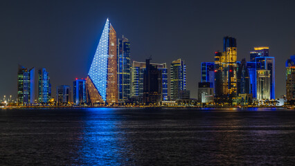 Doha city business downtown center panorama illuminated at night, with modern skyscrapers and sea...