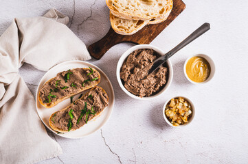 Sandwiches with chicken liver pate and herbs on a plate on the table top view