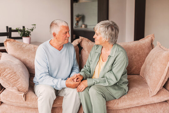 Portrait of a beautiful senior couple embracing each other, sitting on the couch at home