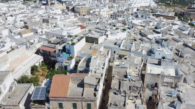 Aerial cityscape of the tourist town of Ostuni, Italy. Aerial view of rooftop of white houses on the hill. Travel destination of Puglia in summer